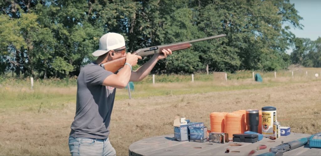 A man shoots a shotgun at a target